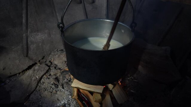 Making organic sheep cheese in wooden mountain Carpathian cheese factory with a boiling smoked cauldron with milk on open fire, Western Ukraine, Europe