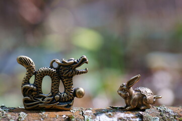 Dragon figurine close-up on a colored background. There is a rabbit figurine next to it. East Asian culture. A spiritual symbol.