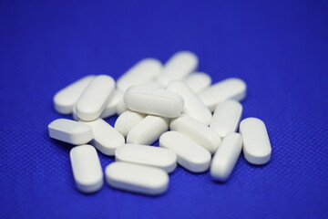 Obraz na płótnie Canvas Heap of medical white pills on a blue background
