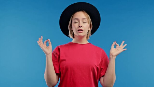 Calm woman relaxing, meditating, refuses stress. Sunny girl breathes deeply, calms down blue studio background. Yoga, moral balance, zen concept.
