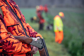 Sicherheit bei der Jagd: Jäger wartet am Feldrand mit nicht schußbereiter Waffe und in...