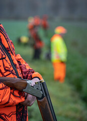 Sicherheit bei der Jagd: Jäger wartet am Feldrand mit nicht schußbereiter Waffe und in...