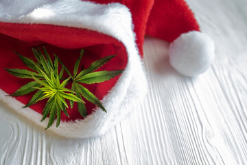 Obraz na płótnie Canvas Cannabis leaf on white. Hemp plant in a basket on a white wooden table