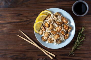 mussels with noodles boiled in a plate with spices on a wooden background