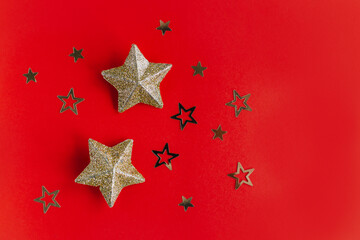 Fototapeta na wymiar Golden sparkling stars on a red background. Flat lay.