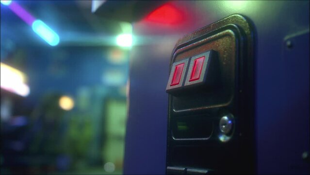 A hand placing a quarter into an arcade machine surrounded by arcade lighting.