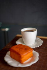 coffee and orange cake on a black background and porcelain tableware on a brown tapere