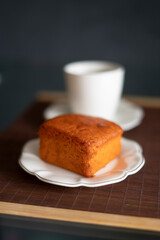 coffee and orange cake on a black background and porcelain tableware on a brown tapere