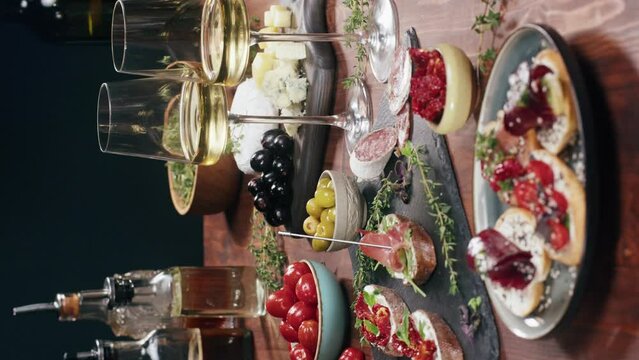 Vertical video, Italian restaurant with traditional food, Spanish cuisine, delicious tapas and white wine, bruschetta with cheese, olives dry tomatoes and tasty sandwich bar appetizer, buffet 