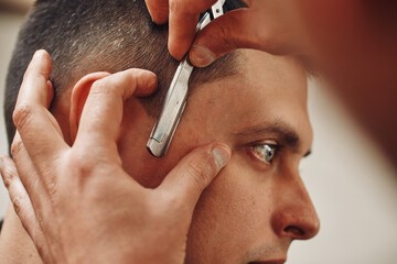 Barber shaving bearded man with retro knife