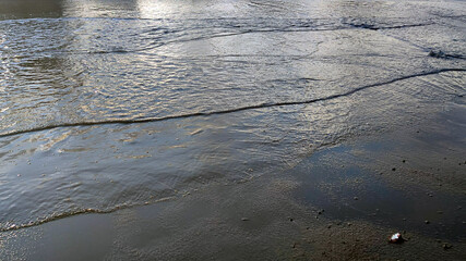Reflection of the sky from the surface of a puddle. A huge puddle has accumulated on the black wet asphalt after the autumn rain. The sky and nearby cars reflect off the surface of the water.
