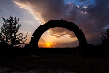 sunset in the desert with stone arch
