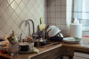 The sink and counter in a rustic kitchen full of pots and pans. Messy Kitchen.
