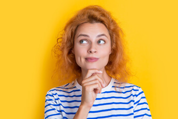 pondering redhead girl face isolated on yellow background. face of young redhead girl in studio