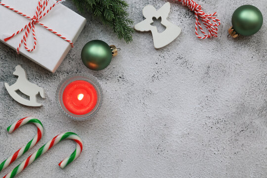 Gift box tied with Christmas rope, candy canes, wooden white horse and angel, red candle, Christmas tree, green Christmas balls