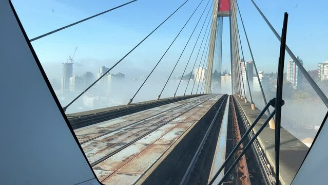 Surrey Vancouver line Skytrain on the bridge The view from the front window on the street fog in the distance you can see the city In the distance one can see skyscrapers in dense smoke in the fog