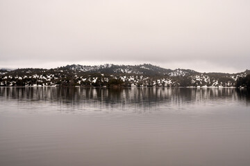 View of the tranquil lake, mountains and forest in a foggy early morning.	
