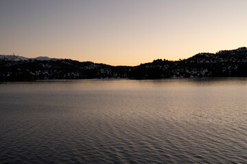 Magical view of the calm lake and mountains at sunset. Beautiful dusk colors in the landscape.