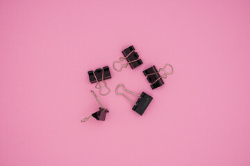 An image of black paper clips on pink background