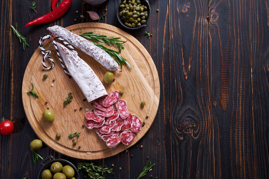 Spanish fuet salami sausageon wooden cutting board at domestic kitchen