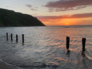 Old weathered posts on beach at sunset, Gardenstown, Scotland