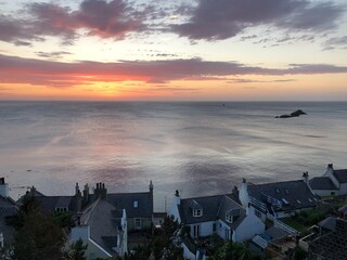 sunset over Gamrie Bay with cottage in foreground, Scotland 
