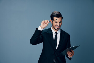 Portrait of a business man in a stylish suit smile with tie beautiful face on a blue isolated background with a tablet in his hands. Business concept young businessman startup copy place