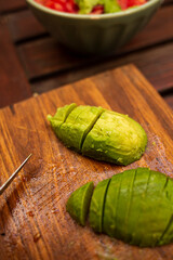 Avocado peeled and sliced on top of a wooden table