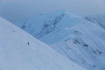 A skier descends a difficult freeride route among rocks and trees