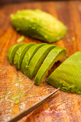 Avocado peeled and sliced on top of a wooden table