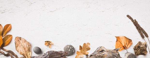 natural autumn / fall banner or background with wood, pebbles and colorful leaves on a white,...