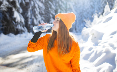 Female runner drinking water at winter day