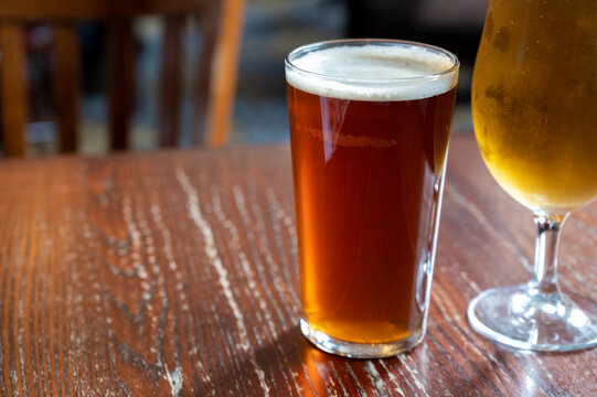 Pint Glasses Of British Ale And Lager Beer Served In Old Vintage English Pub