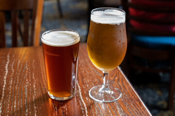 Pint glasses of british ale and lager beer served in old vintage English pub