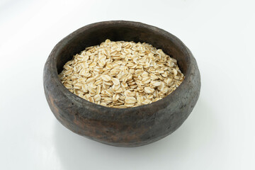raw oatmeal in a rustic bowl on a white background