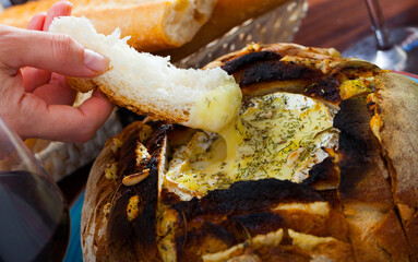 Delicious camembert cheese fondue with dry herbs served in bread bowl