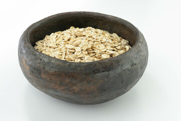 raw oatmeal in a rustic bowl on a white background