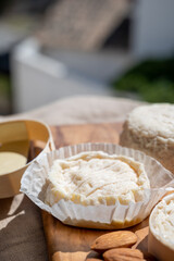 French cheeses Rocamadour and Saint-Marcellin served on olive tree wooden plank with almonds