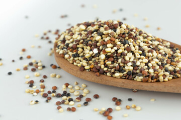 quinoa seed mix in a wooden spoon on white background isolated