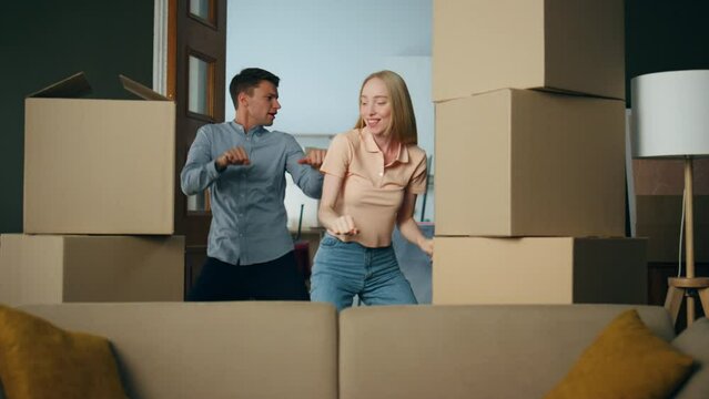 Couple dancing new apartment between packed boxes. Family moving in flat.