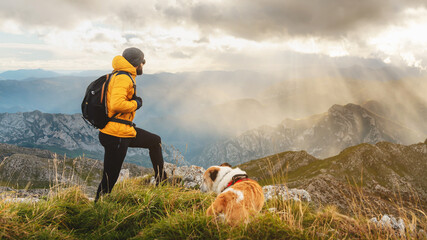 male hiker with backpack, on a rock, contemplating the scenery after climbing a mountain with his...