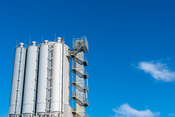 Cylindrical tower of an industrial building against the blue sky.