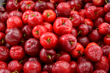 Fresh organic cherry acerolas close-up forming a background pattern.