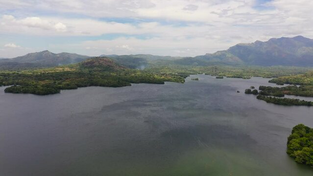 Aerial view of lake with islands surrounded by mountains with a tropical forest. Loggal Oya Reservoir. Sri Lanka.