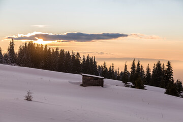Fantastic evening winter landscape with wooden house on the sunset light