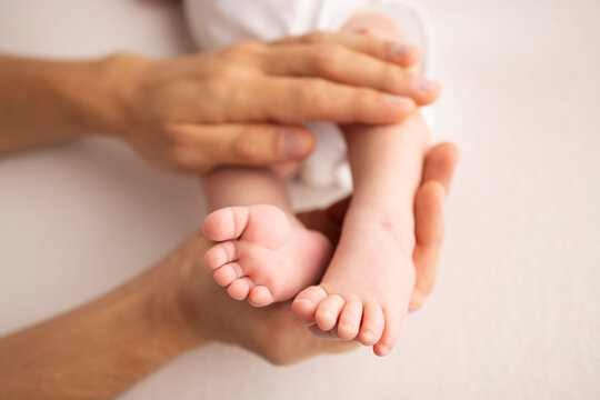 Children's foot in the hands of mother, father, parents. Feet of a tiny newborn close up. Little baby legs. Mom and her child. Happy family concept. Beautiful concept image of motherhood stock photo. 