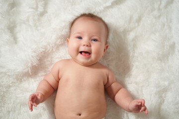 Portrait of an infant on a white background, lying on his back with a joyful expression of emotion