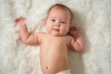 portrait of an infant lying on his back on a white comforter