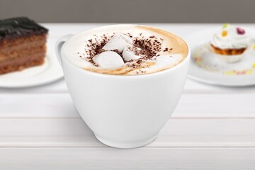 Tasty aroma latte in glass with leaves on the desk