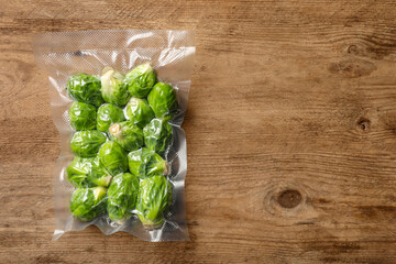 Vacuum pack of Brussels sprouts on wooden table, top view